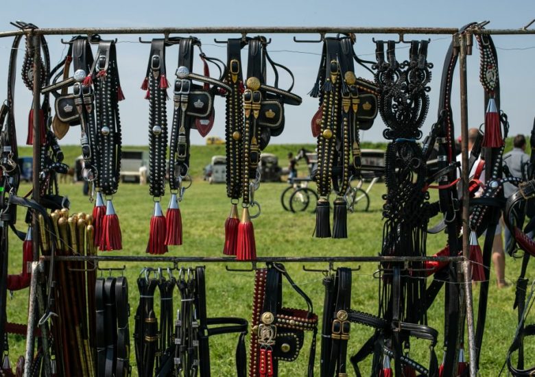 Handmade leather harnesses and tack displayed on racks at an open-air market